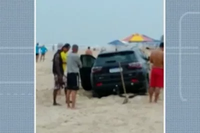 Carro atola na areia da Praia do Flamengo, em Salvador, e banhistas usam pá para retirar veículo